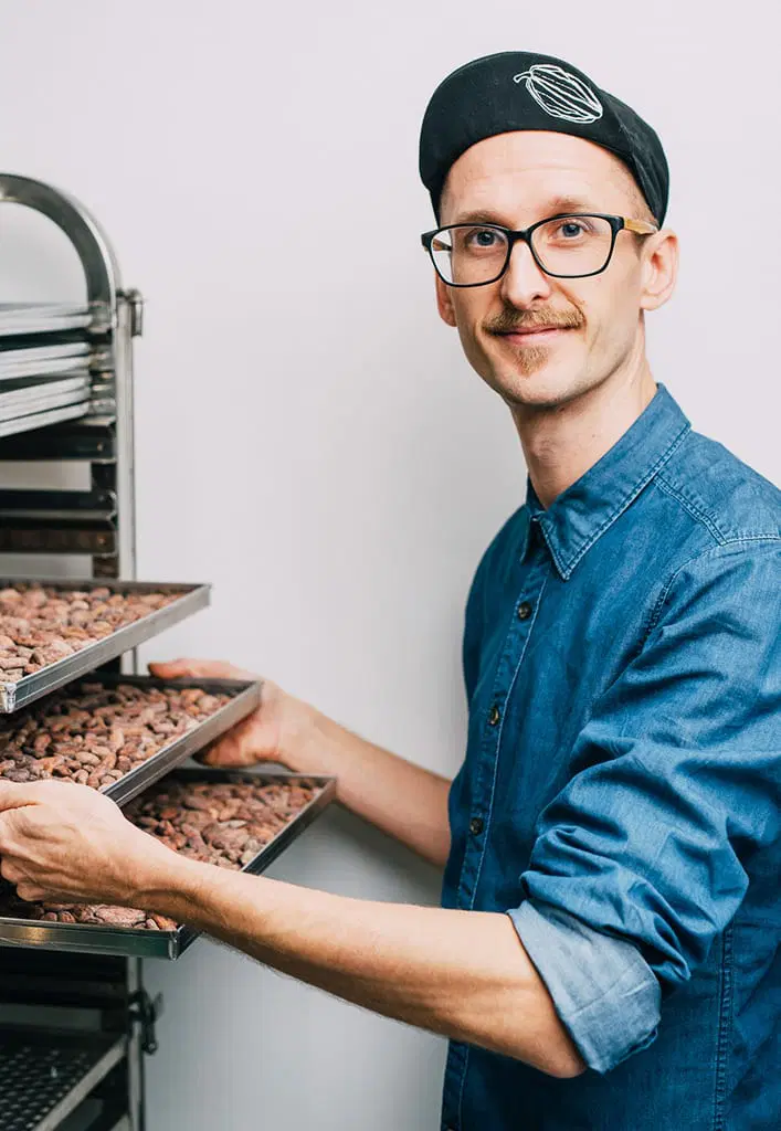 Michael Salge holding trays of cacao beans in the AHERZ workshop.